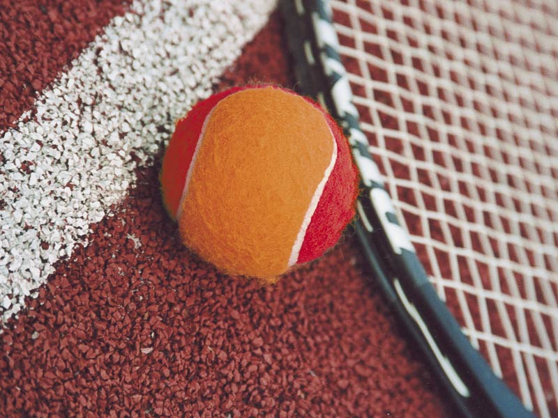 Orangener Play and Stay Tennisball und Tennisschlaeger auf rotem Sandplatz - Kindertennisschule Goer